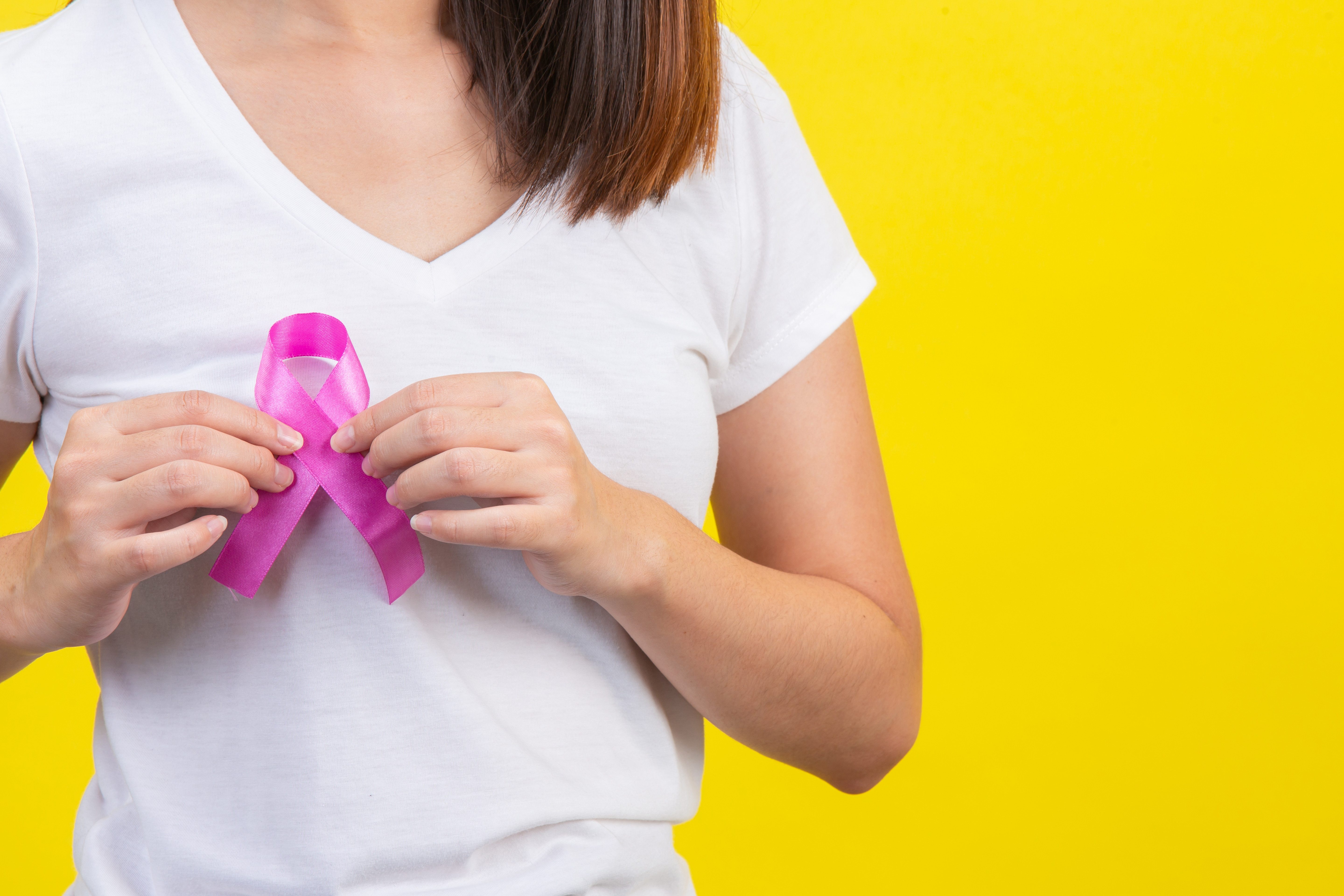 breast-cancer-a-woman-in-a-white-t-shirt-with-a-satin-pink-ribbon-on-her-chest-a-symbol-for-breast-cancer-awareness.jpg